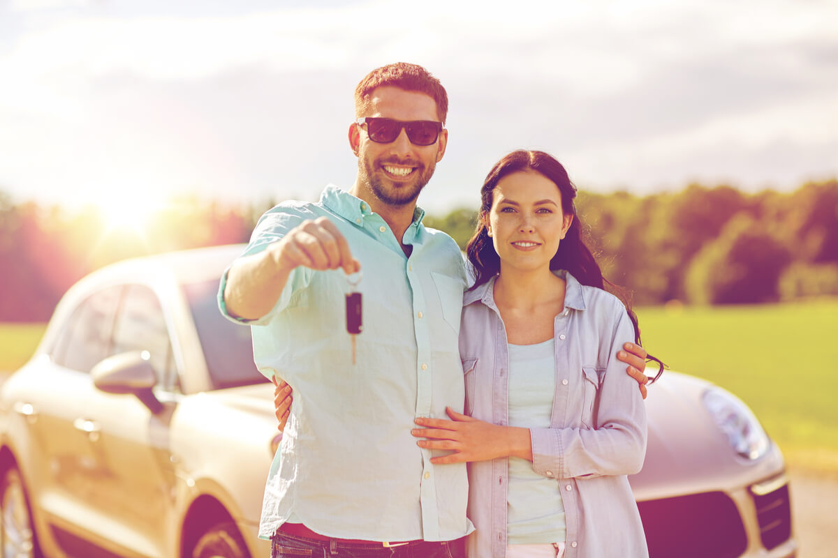 Happy man and woman with car key hugging