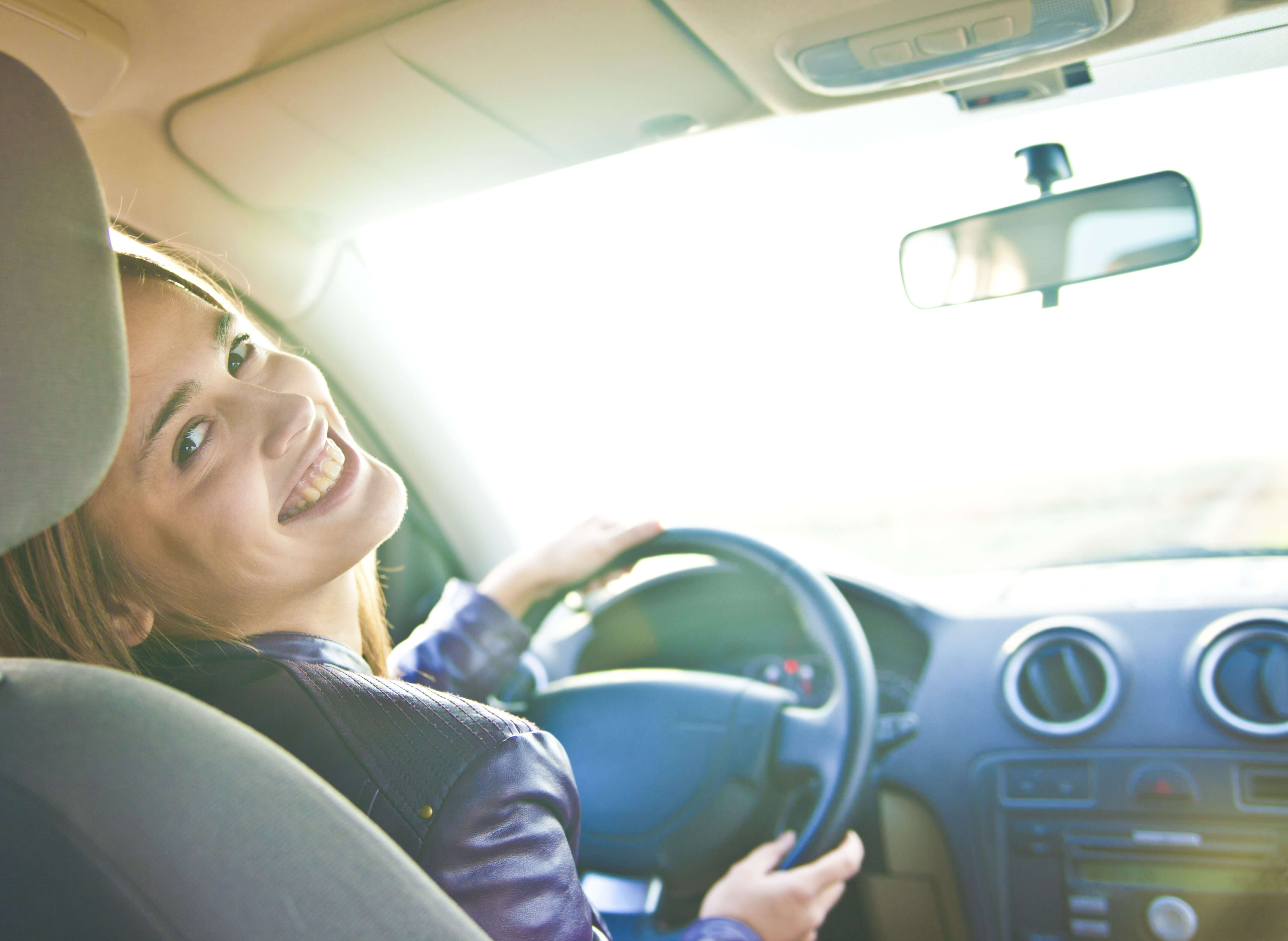 Woman sitting in a newly bought car and smiling